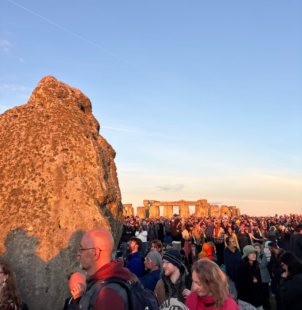 Stonehenge's Heel Stone with Stonehenge in the background.
