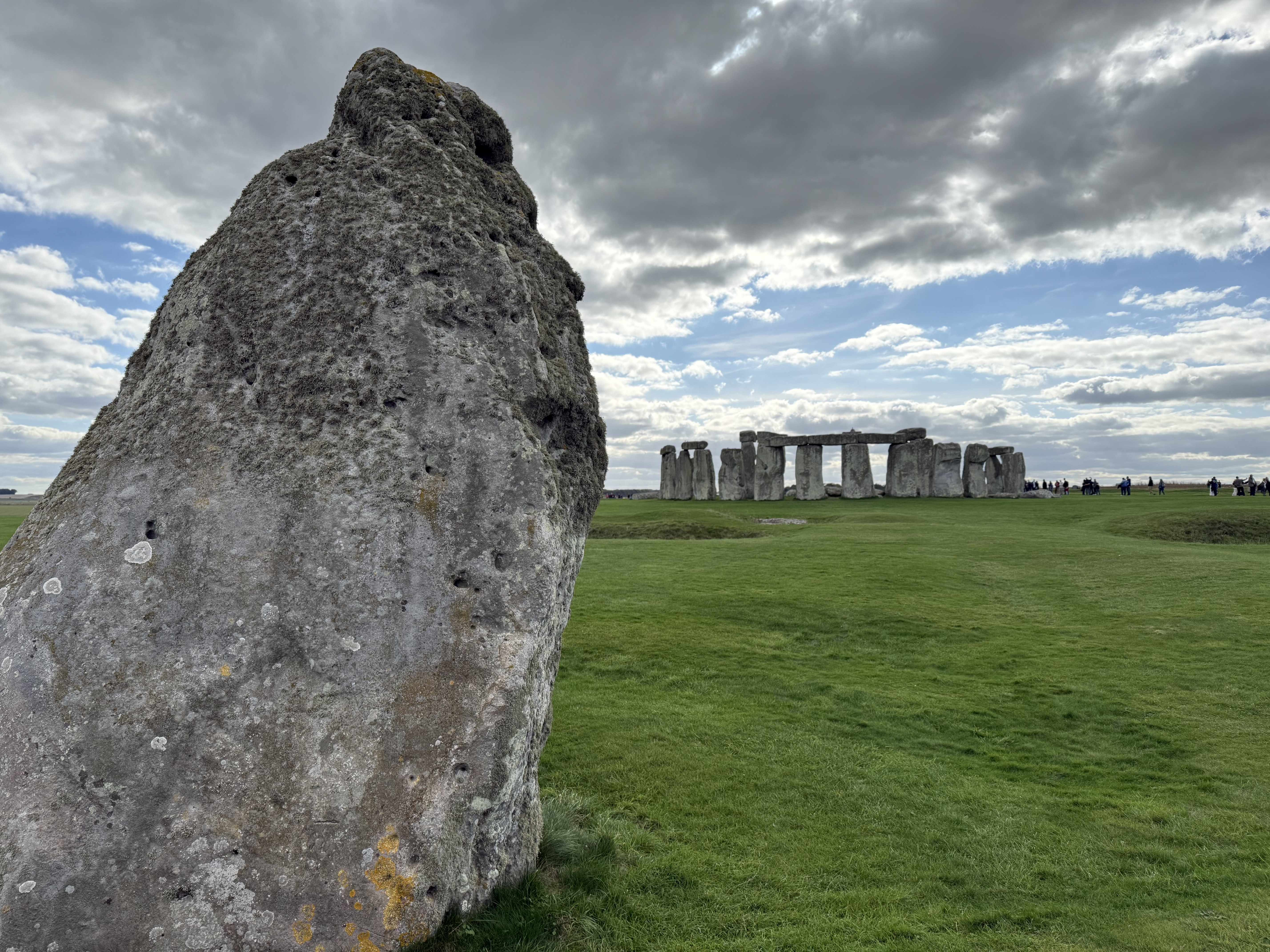 Stonehenge's Heel Stone with Stonehenge in the background.